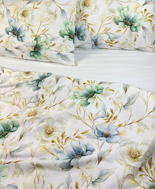 A close-up of a floral bedding set featuring a duvet cover and two pillowcases with a watercolor-style print of blue, green, and cream flowers on a white background.
