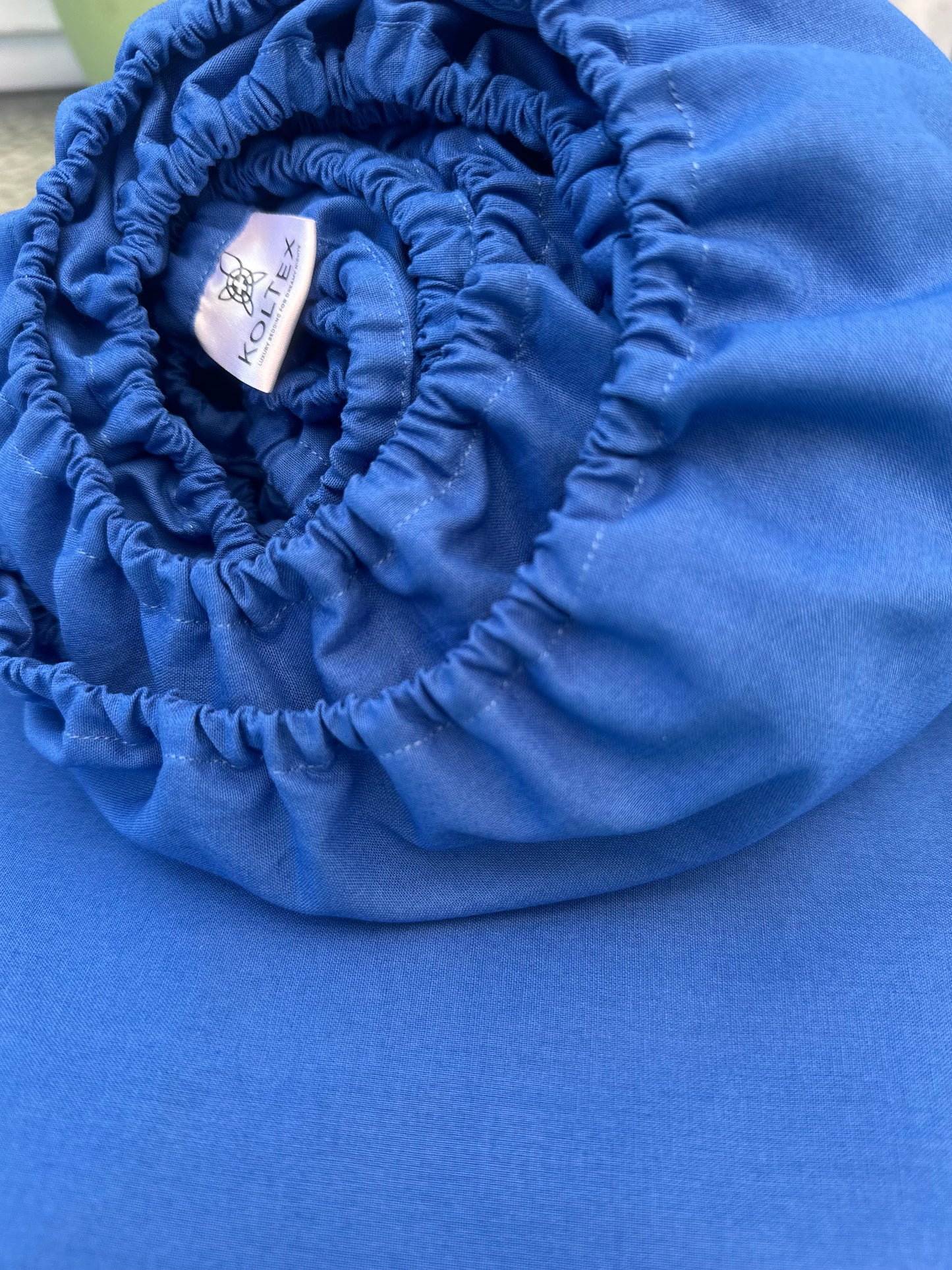 Rolled-up blue fabric with a visible brand label on a blue background