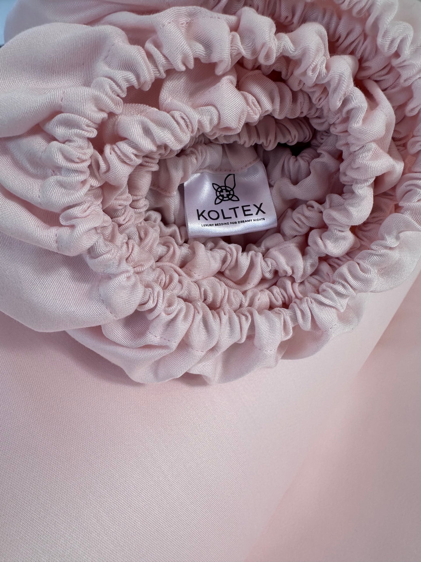 Pink fittes sheets with Koltex label on a pink background