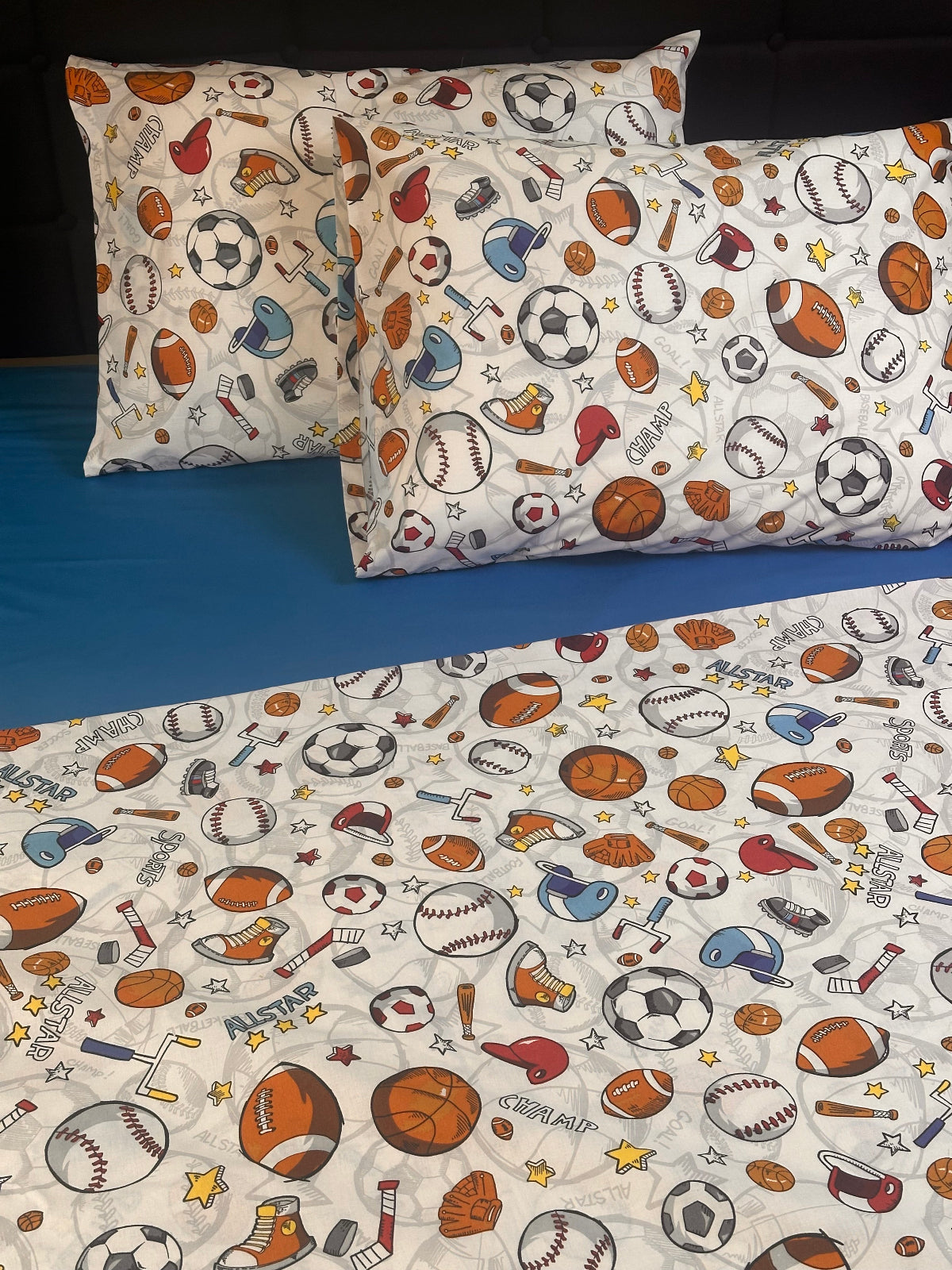 Fun sports pattern pillowcases on blue bed sheet for kids or teens room