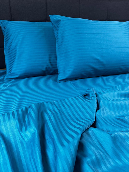 Blue striped bedding on a dark blue bedspread