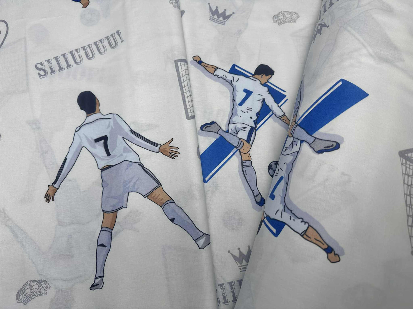 May include: Close-up of two teal-trimmed, white cotton pillowcases featuring a soccer theme. The pillowcases display illustrations of soccer players, goals, and the word 'GOOL!' in a stylized font. One pillowcase also includes a crown graphic. The bedding is ideal for children's bedrooms or sports fans.