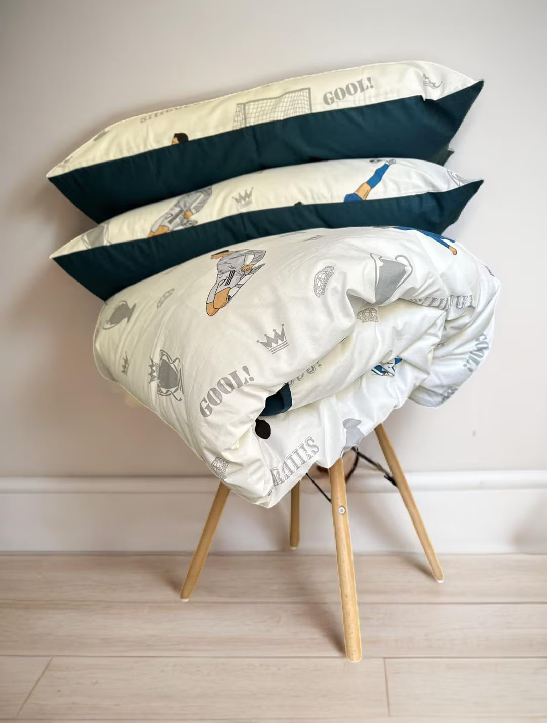 Stack of pillows with space-themed design on a wooden chair against a plain wall.