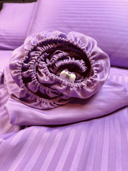 Rolled lavender organic cotton fitted sheet with elastic edge — soft, breathable, hypoallergenic bedding texture