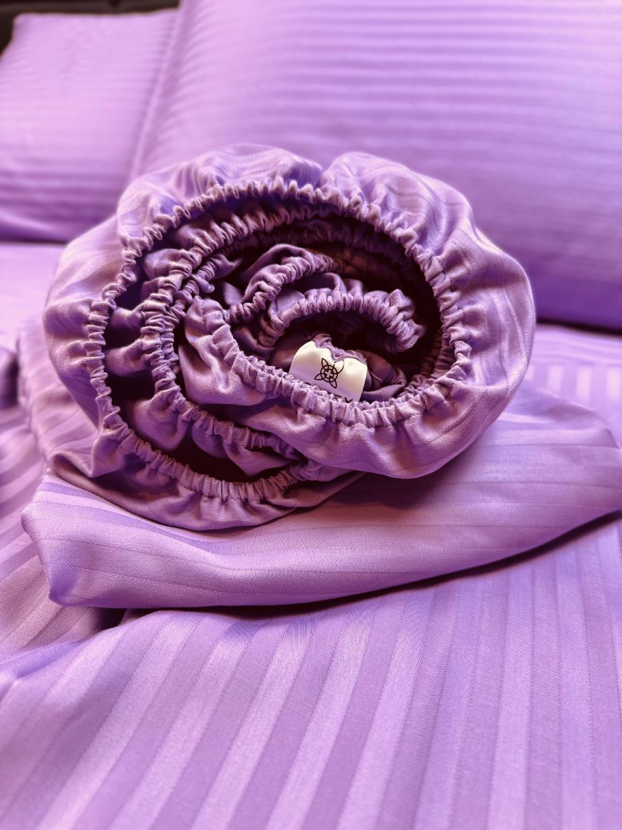 Rolled lavender organic cotton fitted sheet with elastic edge — soft, breathable, hypoallergenic bedding texture