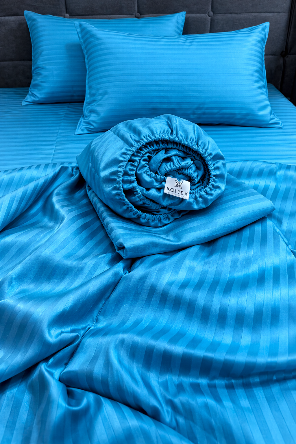 Blue bedding set with pillows and a fitted sheet on a bed.