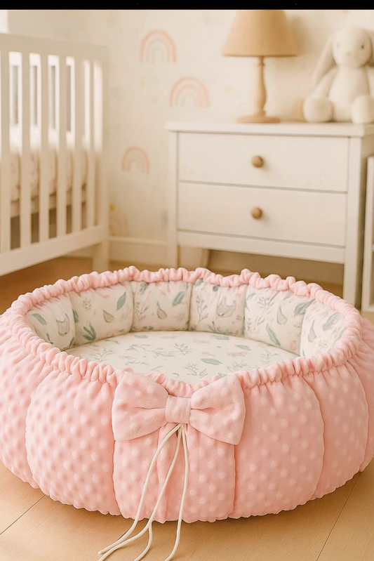 Pink pet bed with a bow in a nursery setting