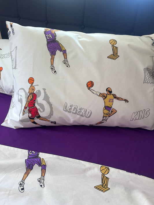 Two white organic cotton pillowcases featuring black basketball player silhouettes in action (dunking and shooting).