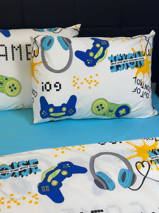 Set of two white organic cotton pillowcases with colorful video game controller print, displayed on a bed