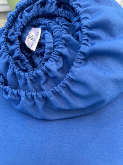 Rolled-up blue fabric with a visible brand label on a blue background