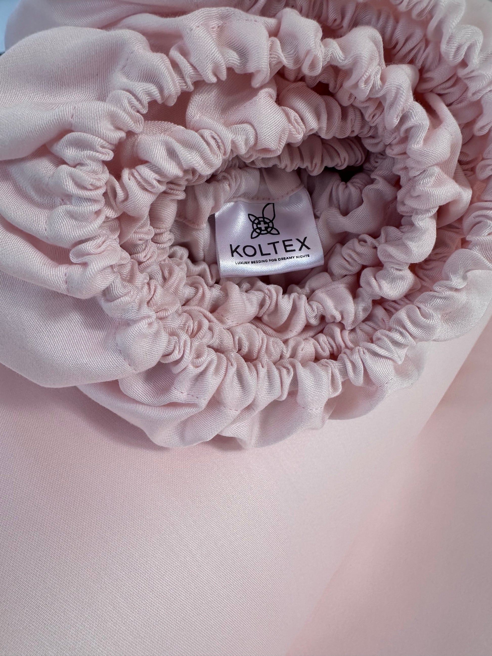 Pink fittes sheets with Koltex label on a pink background