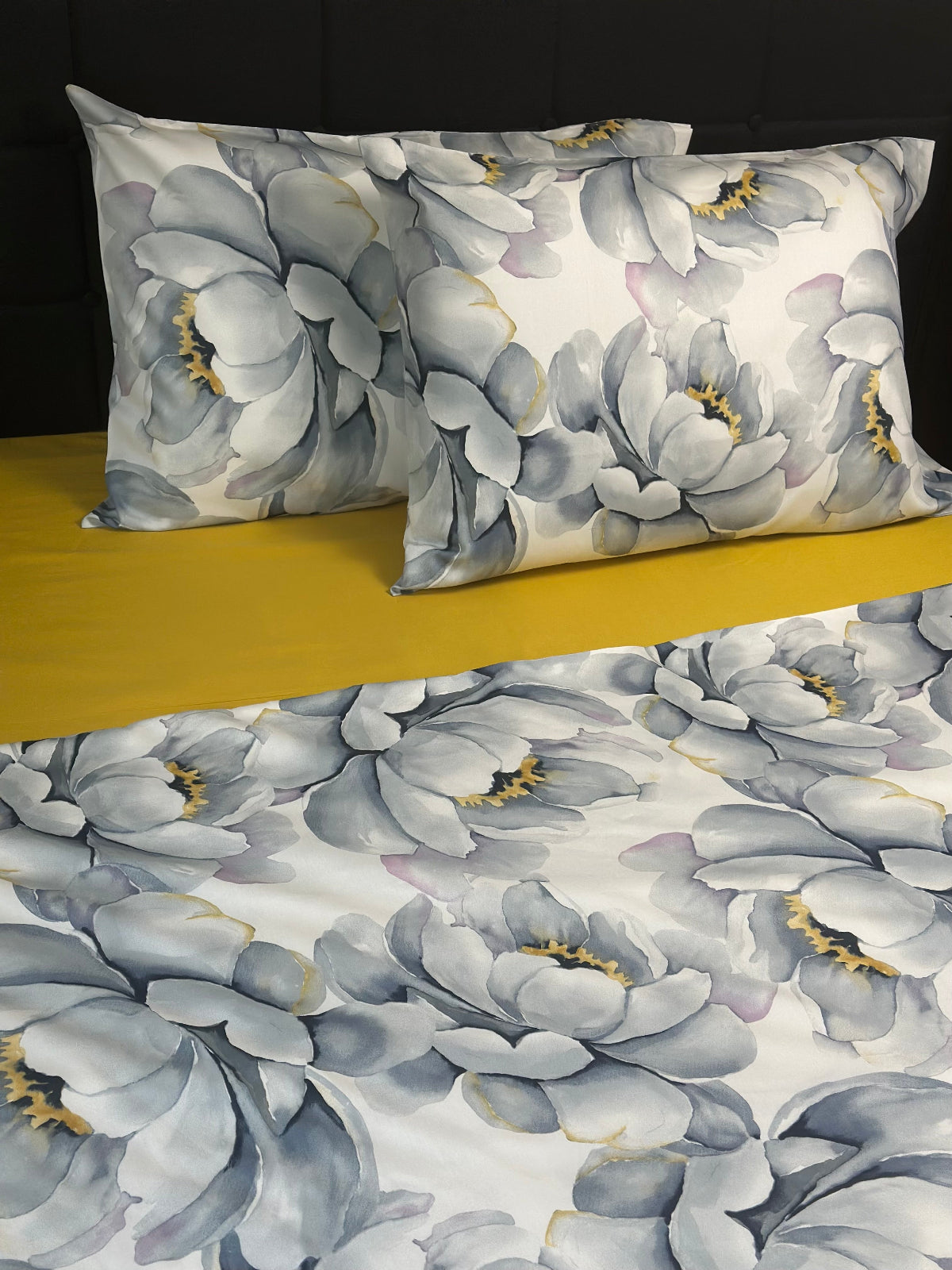 Floral patterned pillowcases on a bed with a yellow blanket