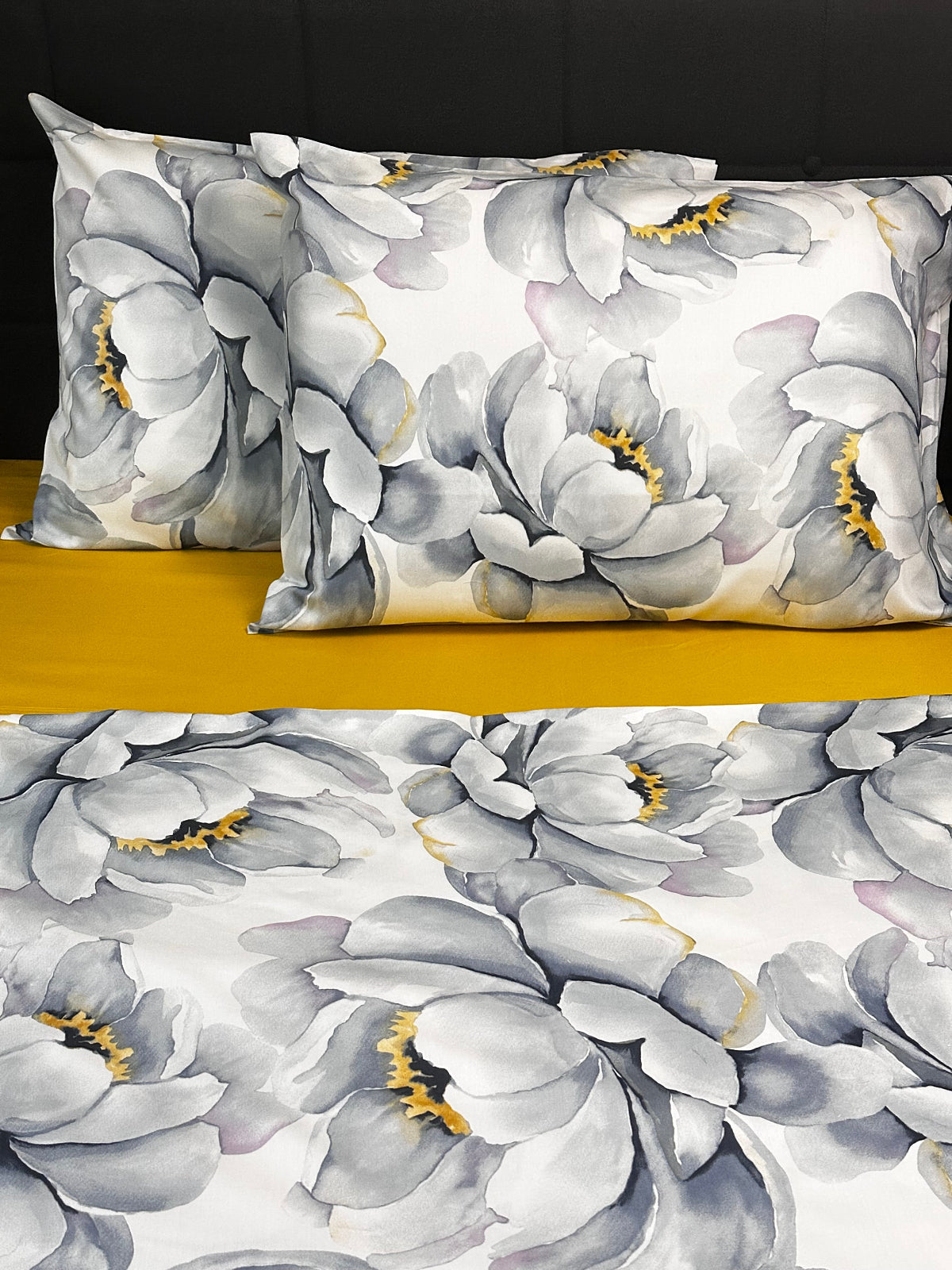 Floral pillowcases with gray flowers and yellow centers on a black background