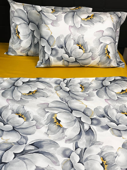 Floral patterned pillow and bedding set on a bed with yellow headboard.