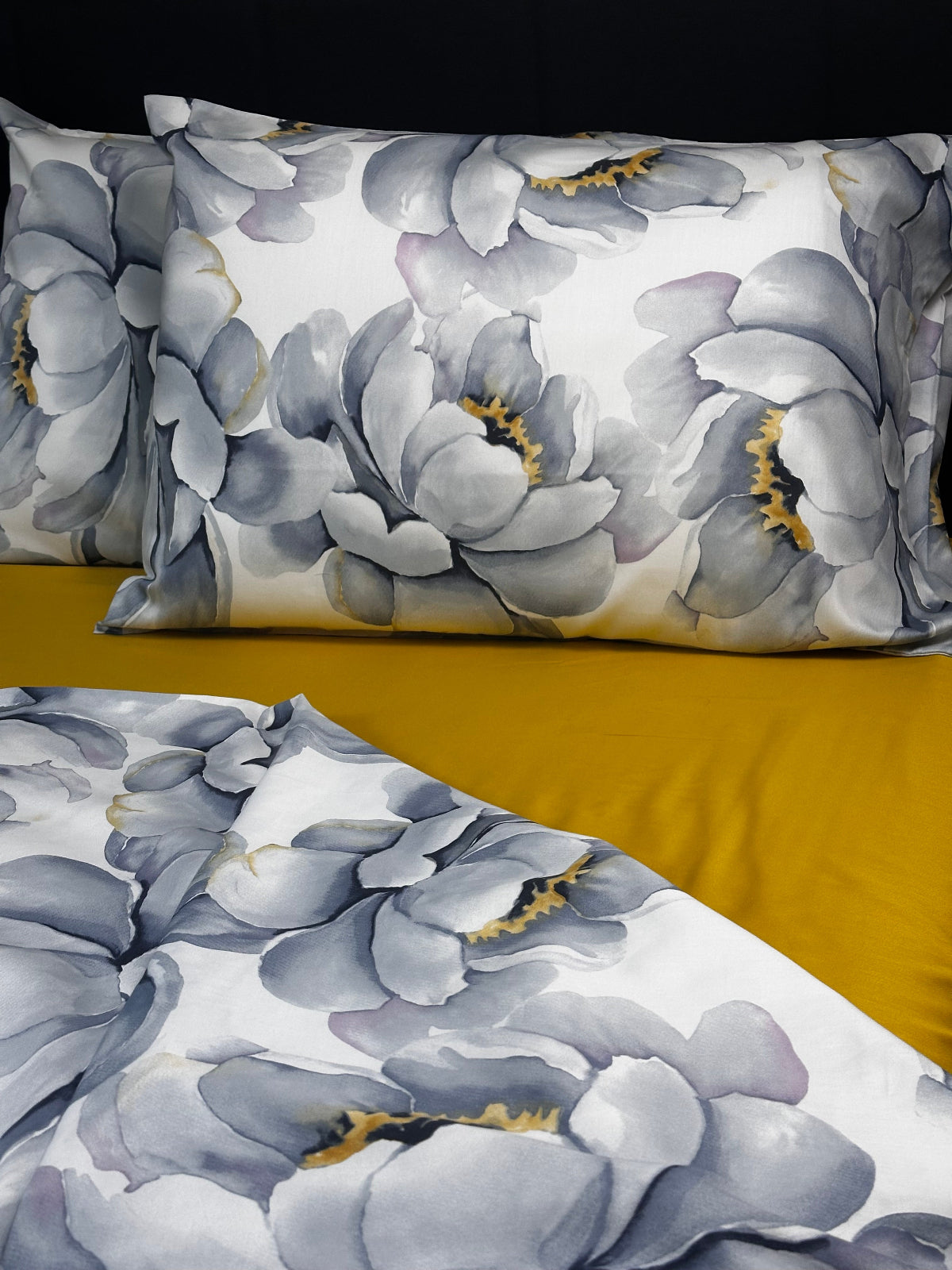 Watercolor peony flower bedding set in soft gray tones, styled on a mustard yellow fitted sheet.