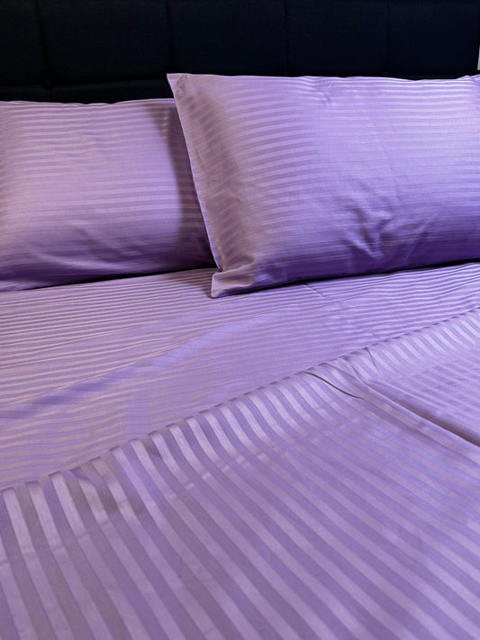 Lavender striped pillowcases on white bedding – soft texture and subtle sheen