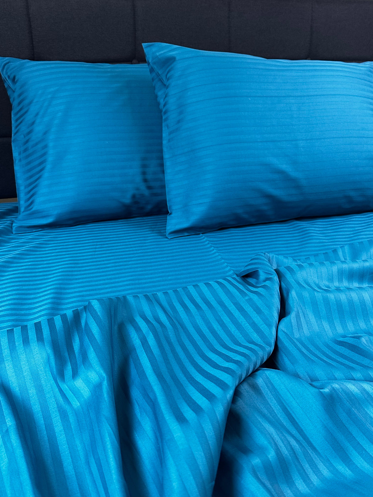 Blue striped bedding on a dark blue bedspread
