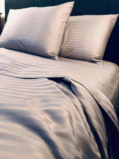 Close‑up of mocha brown striped cotton bedding with smooth sateen texture
