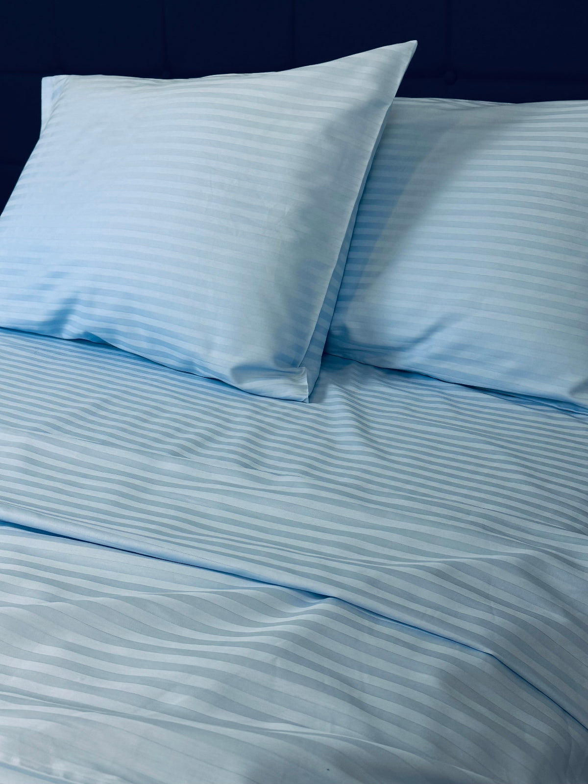 Sky‑blue stripe sateen bedding set made of 100% cotton on a bed