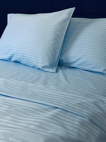 Sky‑blue stripe sateen bedding set made of 100% cotton on a bed