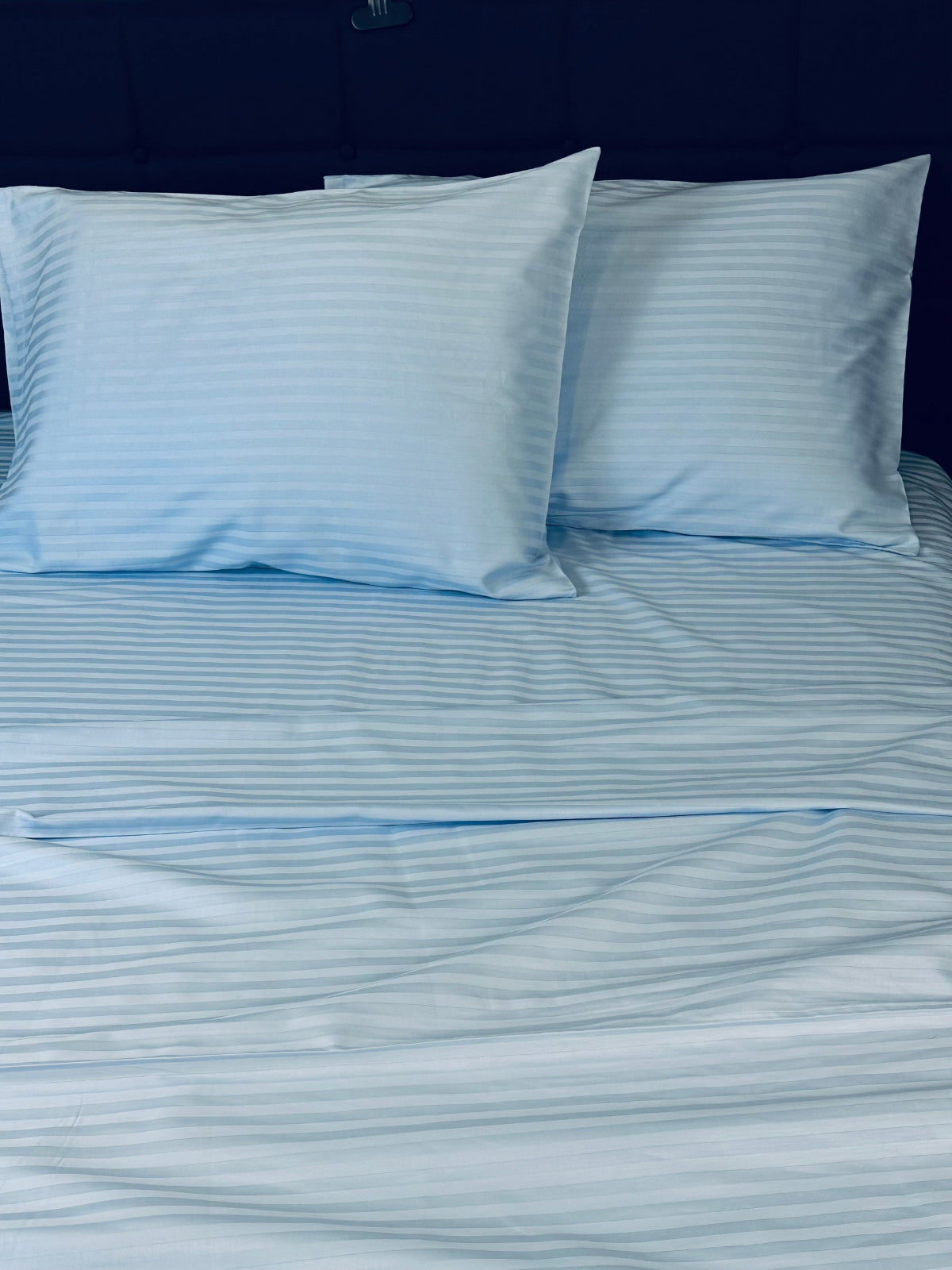 Soft sateen blue striped sheets and pillowcases folded neatly