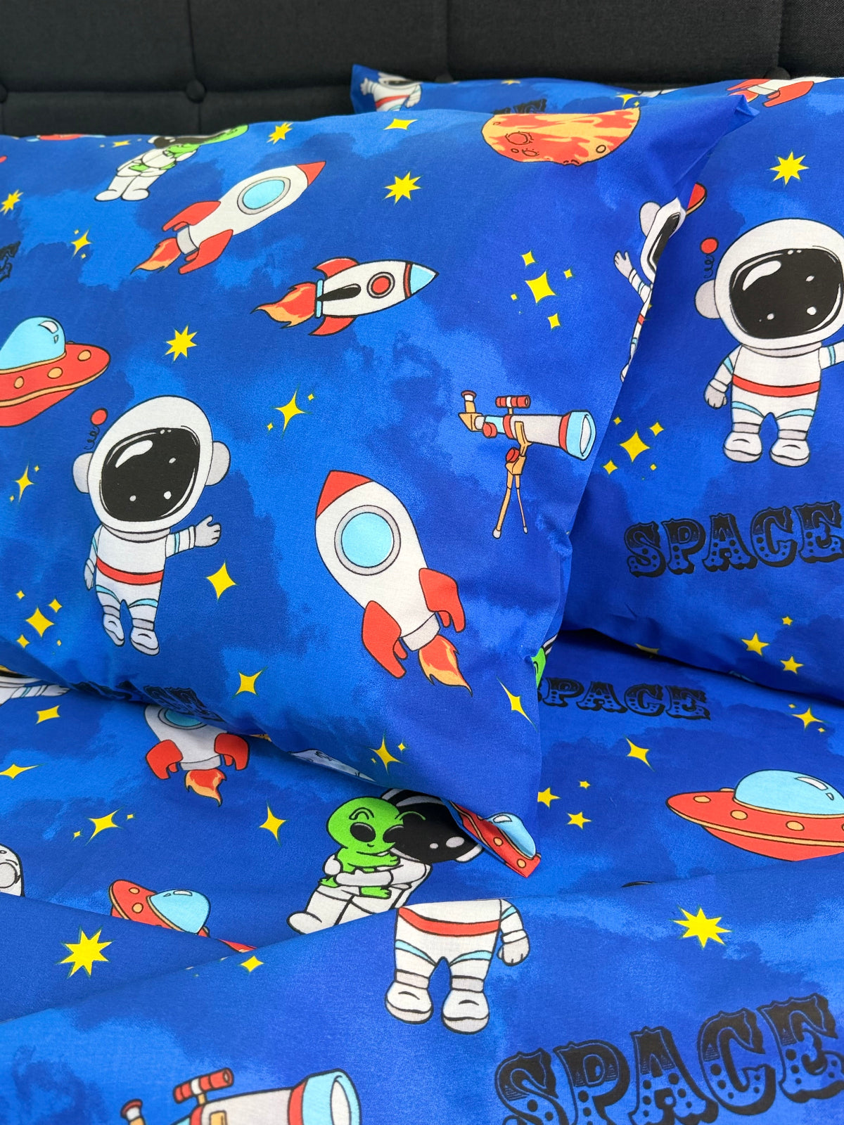 Space-themed fabric with astronauts, rockets, and aliens on a blue background