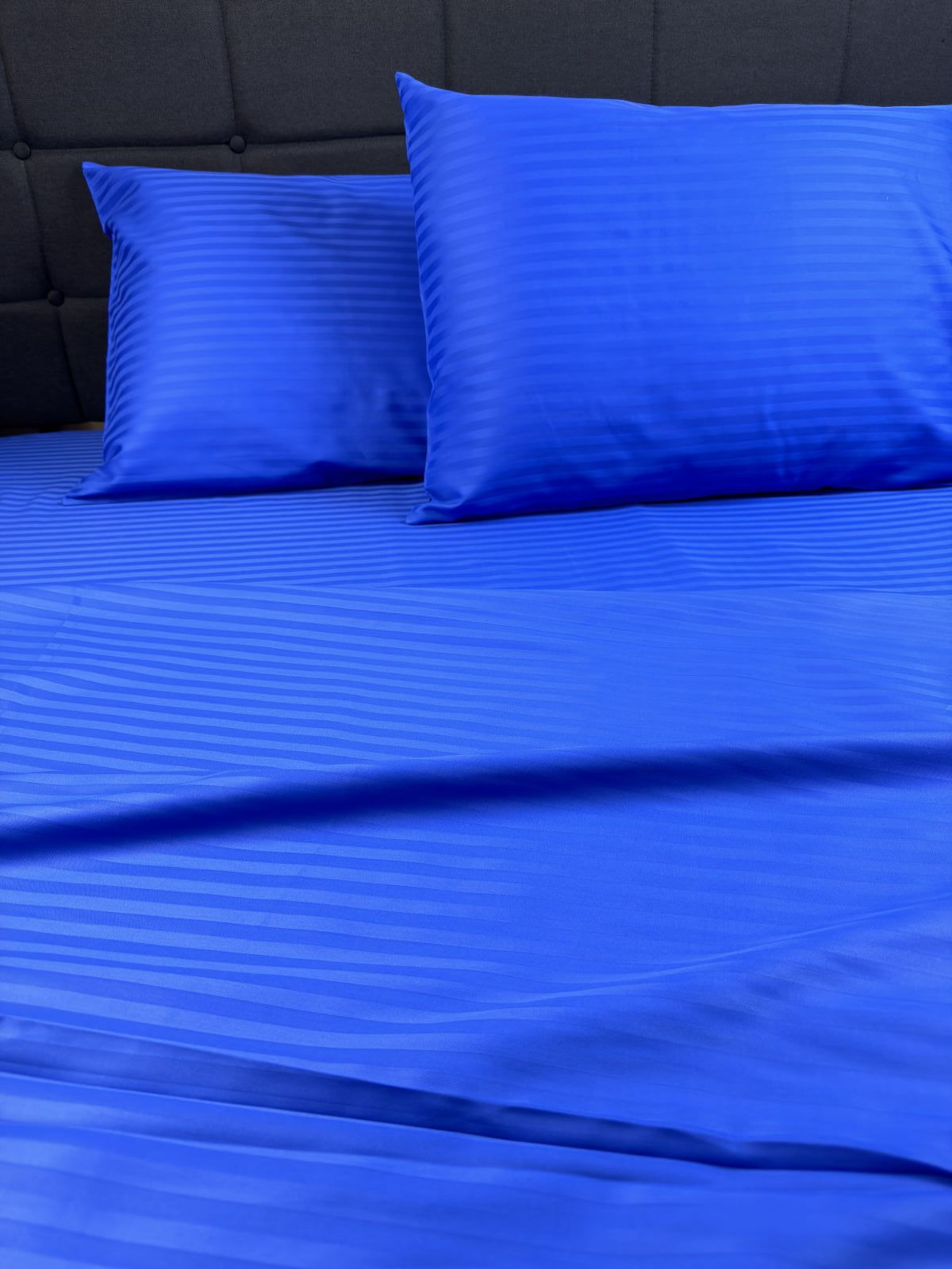 Blue sateen pillowcase on modern bed — soft cotton fabric with subtle sheen.