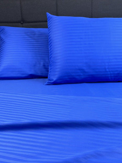 Blue 100% cotton sateen bedding set neatly arranged on bed