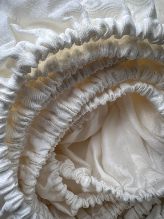 Ivory sateen fitted sheet rolled with soft elastic