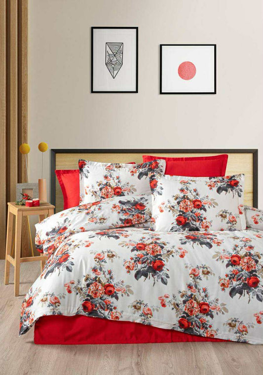 Floral bedding set with red accents on a bed in a bedroom setting.