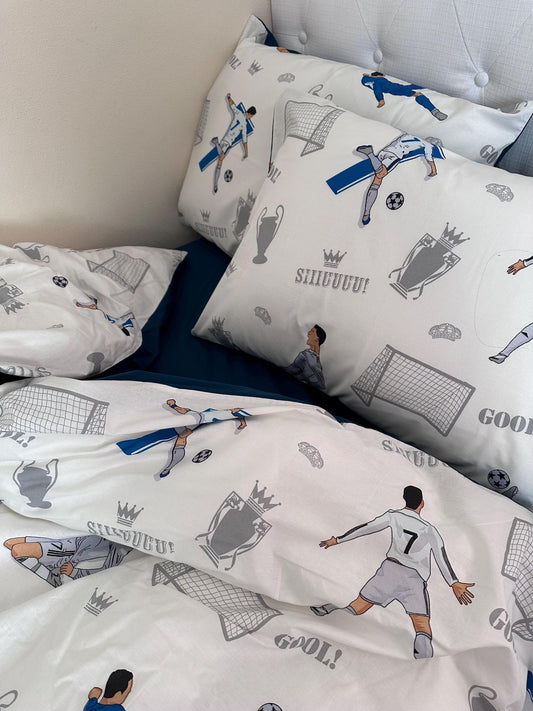 May include: White and blue soccer-themed bedding set. The comforter and pillowcases feature illustrations of soccer players, goals, trophies, and the words 'GOOL!' and 'SHUDUUU!'. The bedding is made of soft, comfortable fabric and is perfect for any soccer fan.